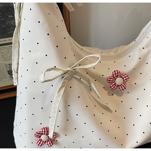 Detail of canvas tote bag with black polka dots, red floral accent and chic bow