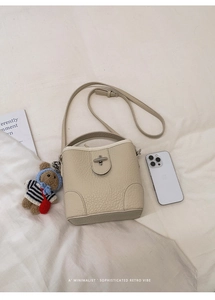 Cream litchi grain bucket bag with a cute bear charm and gold twist lock detail
