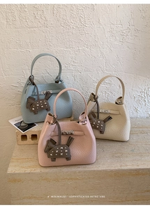 Detail of pebbled leather bucket bags in blue, pink, and beige with metal buckle closure