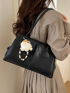 Minimalist black leather tote bag with plush charm and double shoulder straps