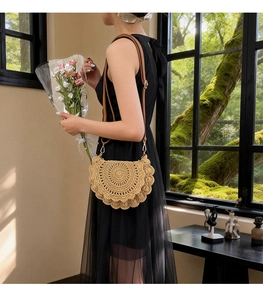 Detail of a beige hollow straw bag with scalloped edges and a brown leather strap