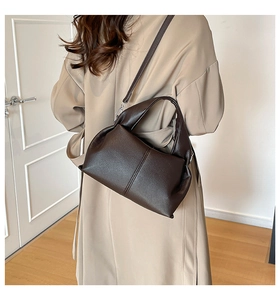 Detail of dark brown lychee leather handbag with shoulder strap on a trench coat model