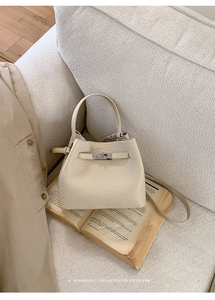 Detail of cream leather bucket bag with metal turn-lock closure on vintage book