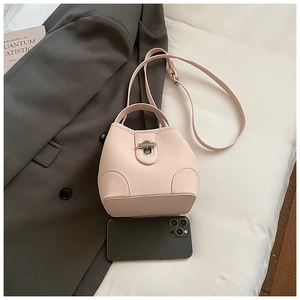 Detail of powder pink bucket bag showing silver metal lock and smooth PU leather texture