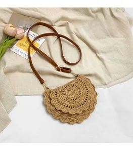 Detail of hollow straw saddle bag with brown leather strap and golden metal clasp