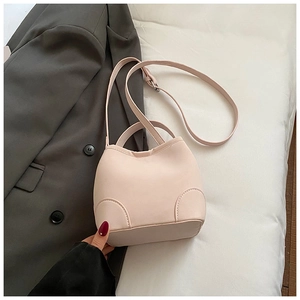 Detail view of pink leather handbag with curved base and dual handles on grey suit