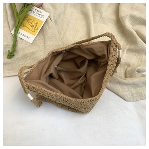 Detail of the large straw beach bag featuring a brown fabric lining and secure zipper pocket