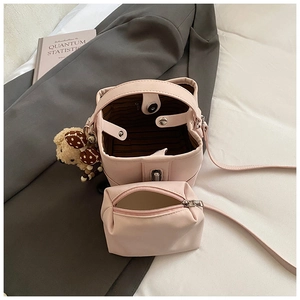 Detail view of pink bucket bag set with inner pouch and plush bear charm accessory