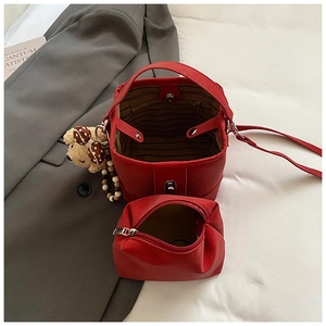 Red bucket bag set with inner pouch and plush bear charm on a suit fabric background