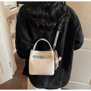 Detail of contrast color bucket bag featuring litchi grain leather and metal turn-lock