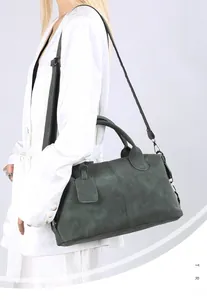 Model wearing dark green Boston bag with detachable strap over a white satin blazer
