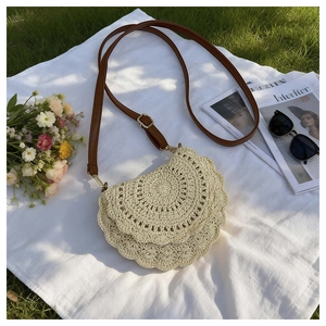 Detail of a woven cream saddle bag on a white picnic cloth with floral garden accents
