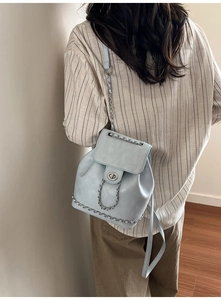 Détail d'un sac à dos en cuir bleu clair avec chaînes argentées et fermoir rotatif