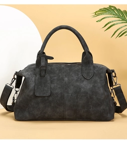 Detail of dark gray suede Boston bag with dual handles and matte gunmetal hardware