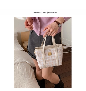 Detail of checkered bucket bag with fine embroidery and golden hardware accents