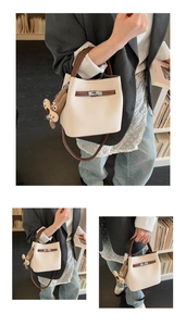 Detail of cream bucket bag with lychee texture, silver lock, and plush monkey charm