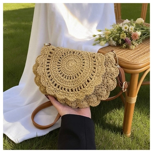 Detail of hand-woven beige straw saddle bag with scalloped edges and leather strap