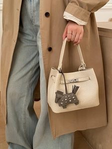 Elegant off-white lychee leather bucket bag with metal twist lock and horse charm