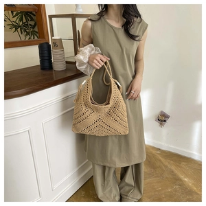 Detailed view of hand-woven straw tote with natural fiber texture and tassel accents