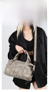 Close-up of gray vintage textured handbag with round handle and adjustable shoulder strap