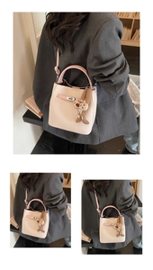 Detail of a dual-tone bucket bag with metal lock buckle and plush puppy charm
