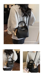 Close-up of black lychee leather bucket bag with silver twist lock and plush rabbit charm
