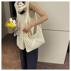 Close-up of beige crochet shoulder bag with hollow geometric patterns and a tulip bouquet