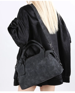 Detailed back view of a grey suede Boston bag with crossbody strap on a model