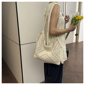 Detail of cream crochet beach bag with hollow geometric patterns and tassel straps