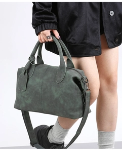 Moss green Boston bag in matte suede texture shown being held by a model