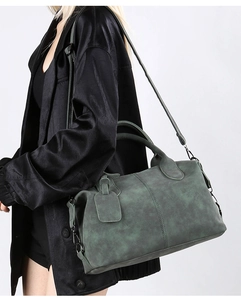 Detail of vintage dark green Boston bag showing textured leather and round handles