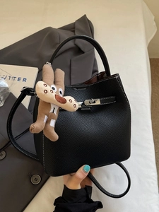 Fashionable black pebbled leather bucket bag with top handle and brown dog charm