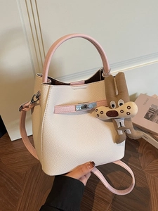 Contrast color bucket bag in beige leather with pink handles and plush charm accessory