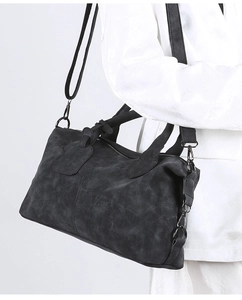 Detail view of a black vintage Boston handbag with adjustable strap and matte hardware