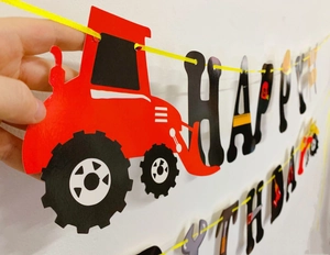 Close-up of Happy Birthday banner with construction vehicle patterns and yellow ribbon