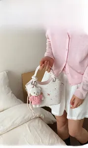 Detail of white floral bucket bag with pink bow print and cute teddy bear charm