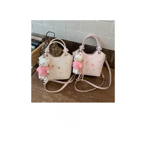 Detail of trendy crossbody bucket bags with cartoon prints and plush bear charms