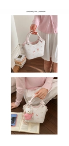 Detail of white bucket bag with bear print, pink handle and cute plush charm pendant