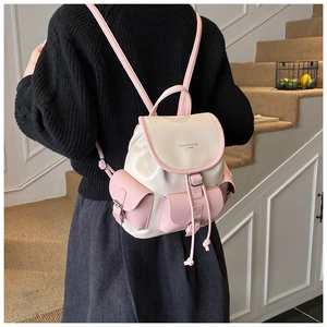 Detailed back view of model wearing a two-tone pink and cream leather drawstring backpack