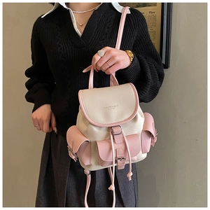 Detail of contrast-color backpack featuring lychee texture leather and metal buckles
