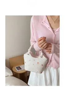 Close-up of cream bucket bag featuring cute cat prints and woven knot handle detail