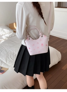 Detail of pink cartoon pattern handbag with adjustable strap worn by a model