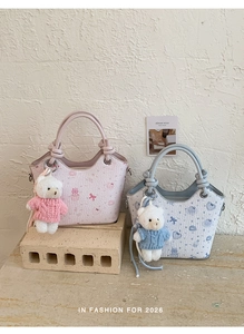 Detail of printed bucket bag featuring cute cat patterns and teddy bear plush charm