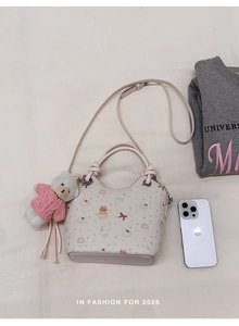 Detailed close-up of a printed bucket bag with a cute bear charm and pink strap