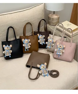 Six colors of leather bucket bags with teddy bear charms on a sofa setting