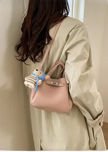 Détail du sac à main en cuir rose avec fermoir argenté et breloque ours mignonne