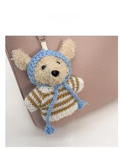 Detail of crochet bear bag charm in striped sweater on pink pebble leather handbag