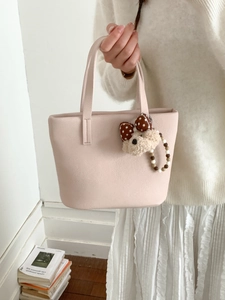 Detail of light pink felt tote bag featuring a cute brown polka dot bear charm