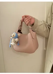 Close-up of pink lychee textured leather bucket bag featuring a cute teddy bear charm
