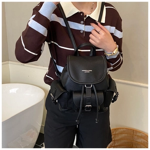 Close-up of a black lychee texture leather backpack with metal buckles on a model
